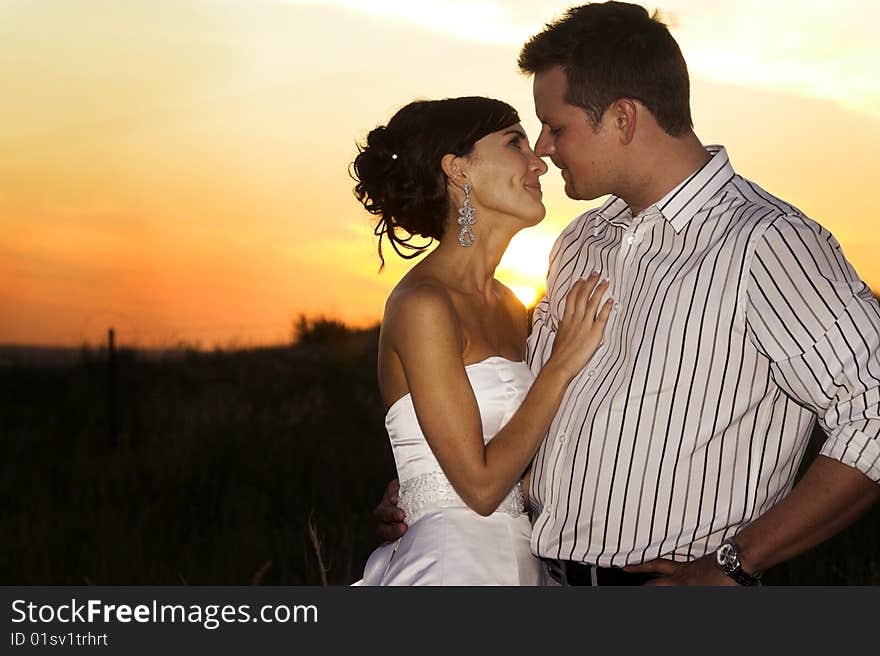 Bridal couple in the field as the sun sets