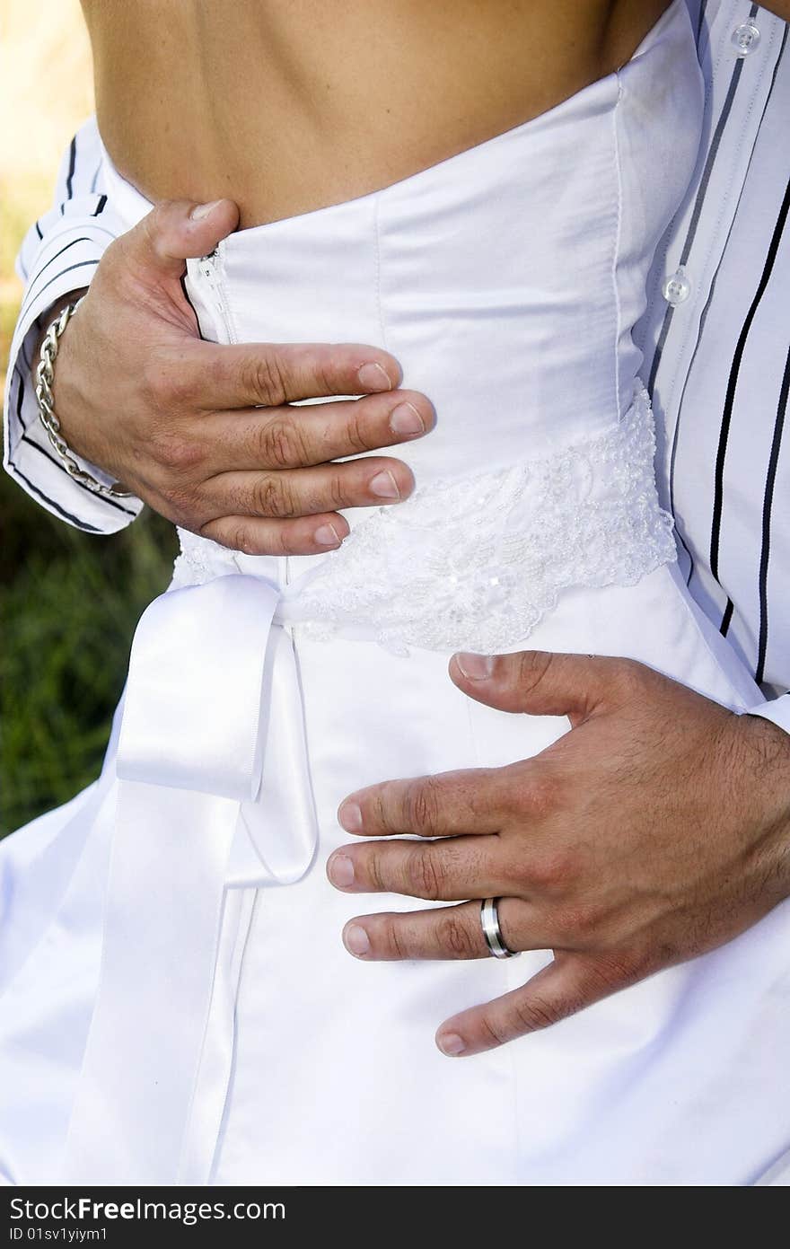 Groom holding his new bride's gently around her waist. Groom holding his new bride's gently around her waist