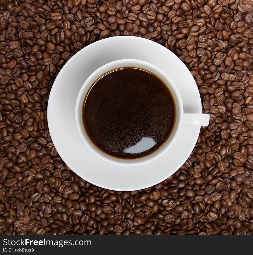 Cup of coffee sitting in a bed of coffee beans isolated over a white background