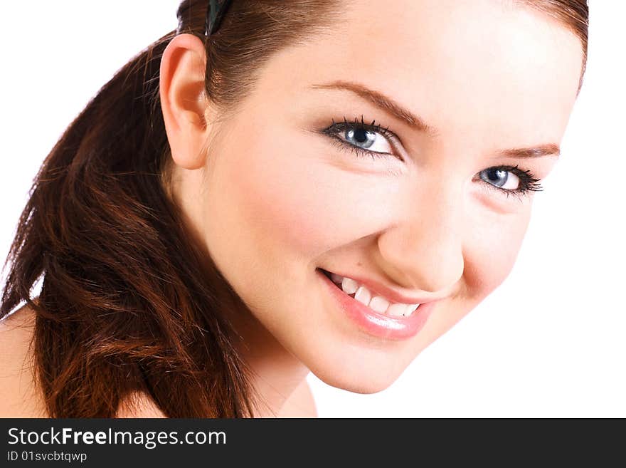 A close up of a beautiful brunette smiling at the camera in front of a white background.