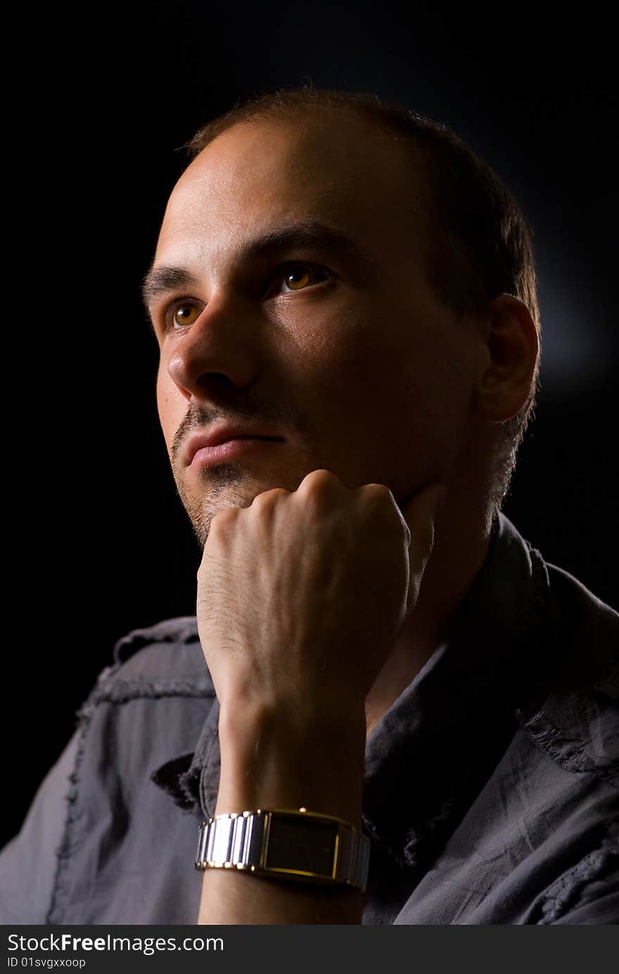 Young man thinking. Dark background