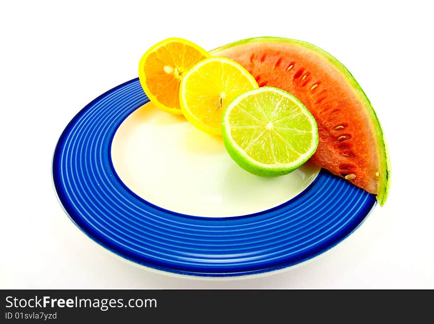 Slice of red juicy watermelon with lemon, lime and orange halves on a blue plate with a white background. Slice of red juicy watermelon with lemon, lime and orange halves on a blue plate with a white background