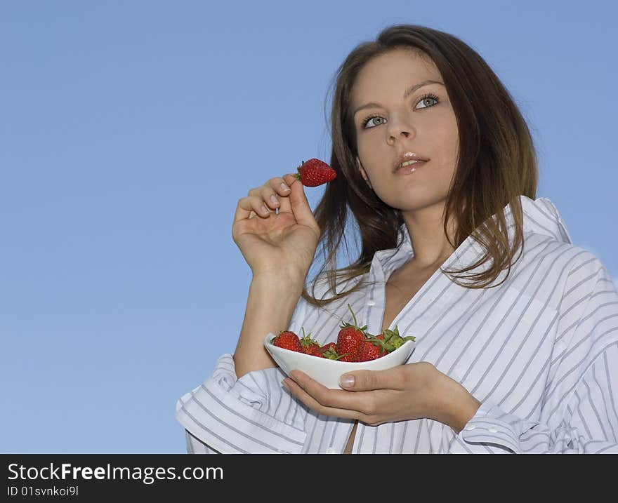 Pretty girl relaxing on balcony and eat red fresh strawberry.