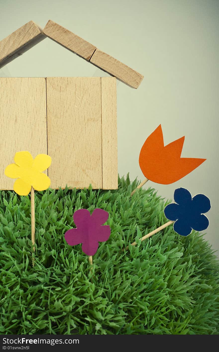 Wooden model of house on green grass