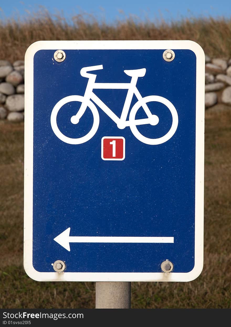 Blue Sign with Bicycle and Stonefence in Background. Blue Sign with Bicycle and Stonefence in Background