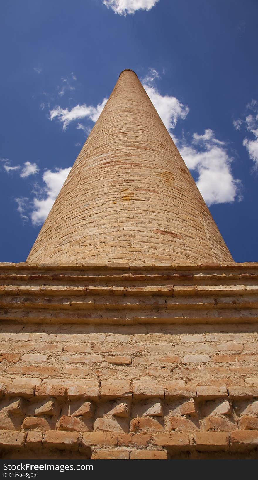 An old brick chimney against the blue sky