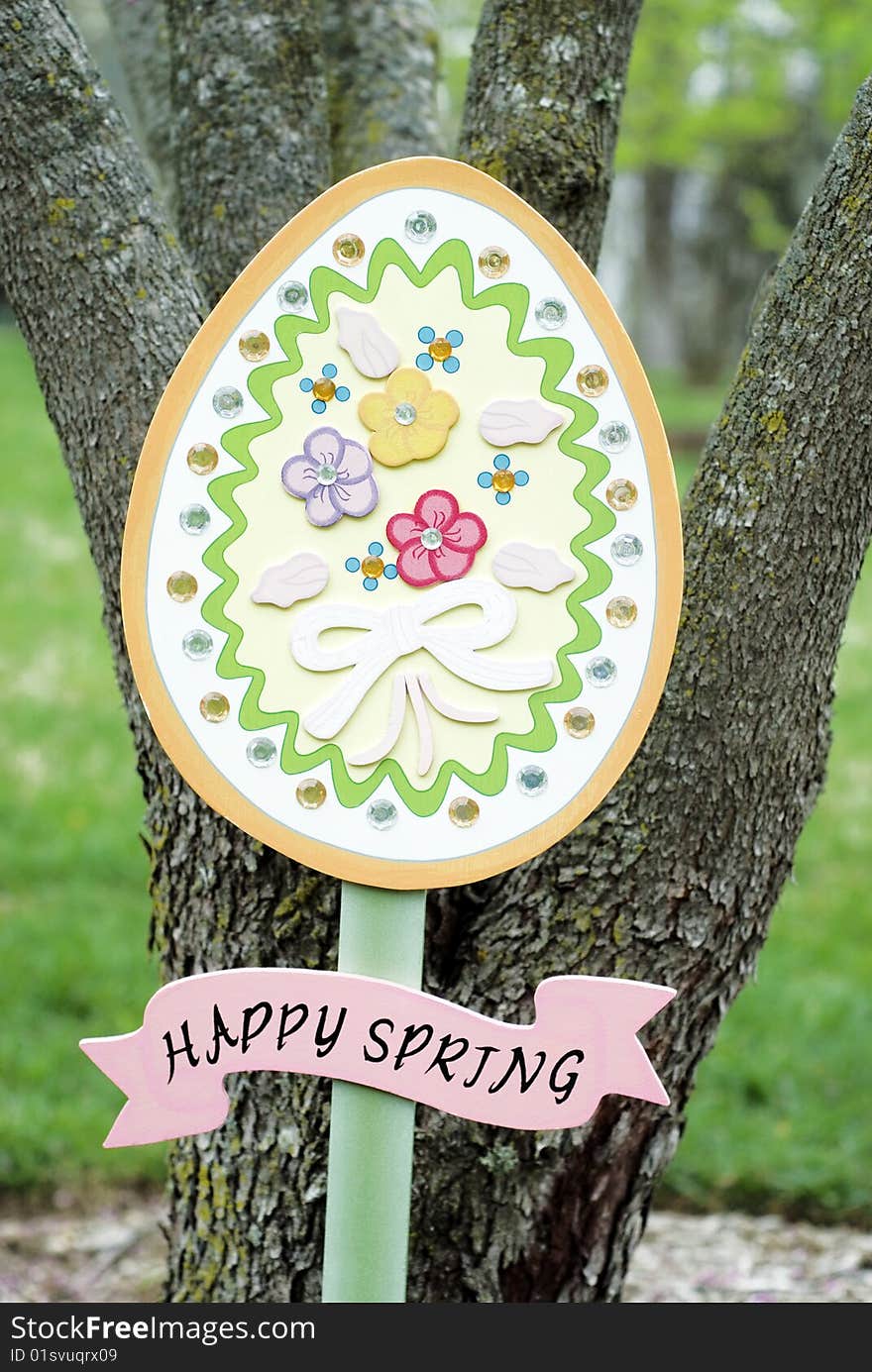 A colorful wooden Easter egg Happy Spring garden sign, vertical with copy space