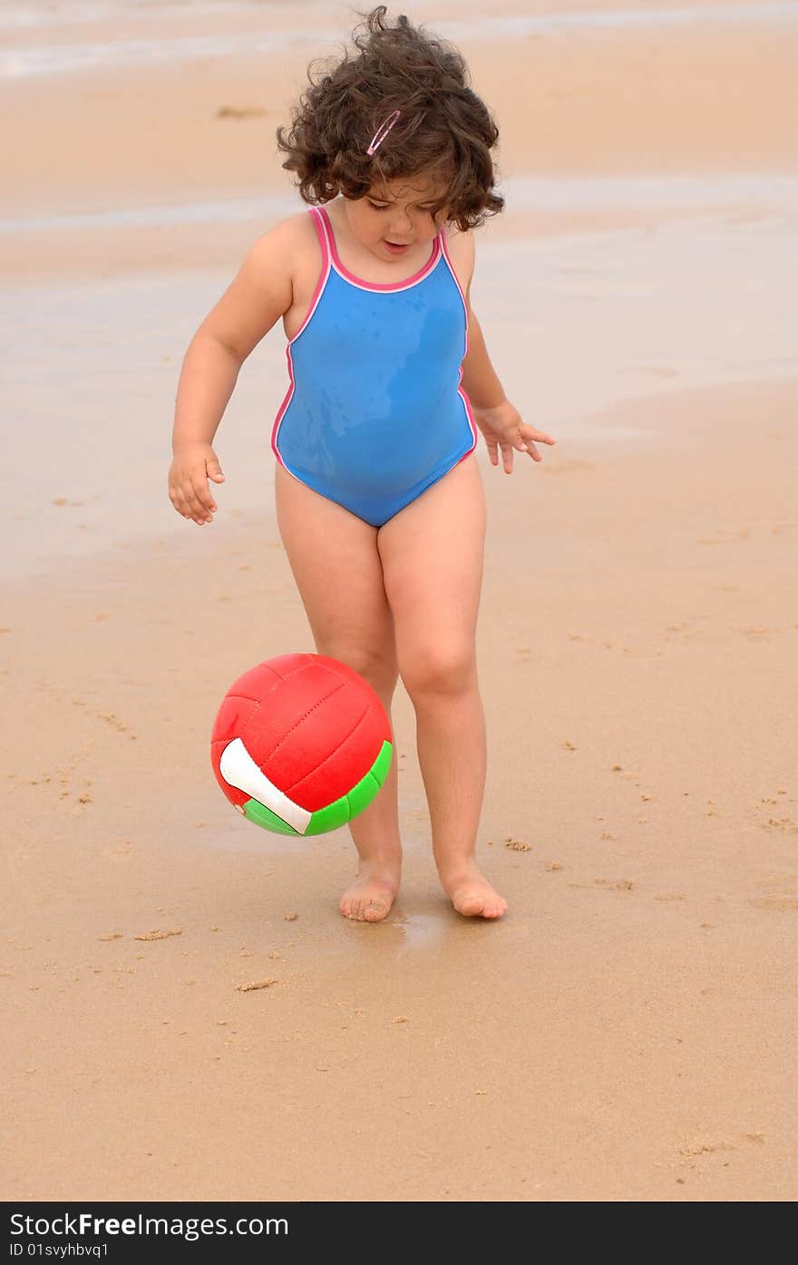 Cute little girl on the beach playing with a ball