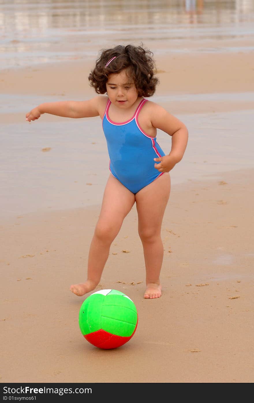 Cute little girl on the beach playing with a ball