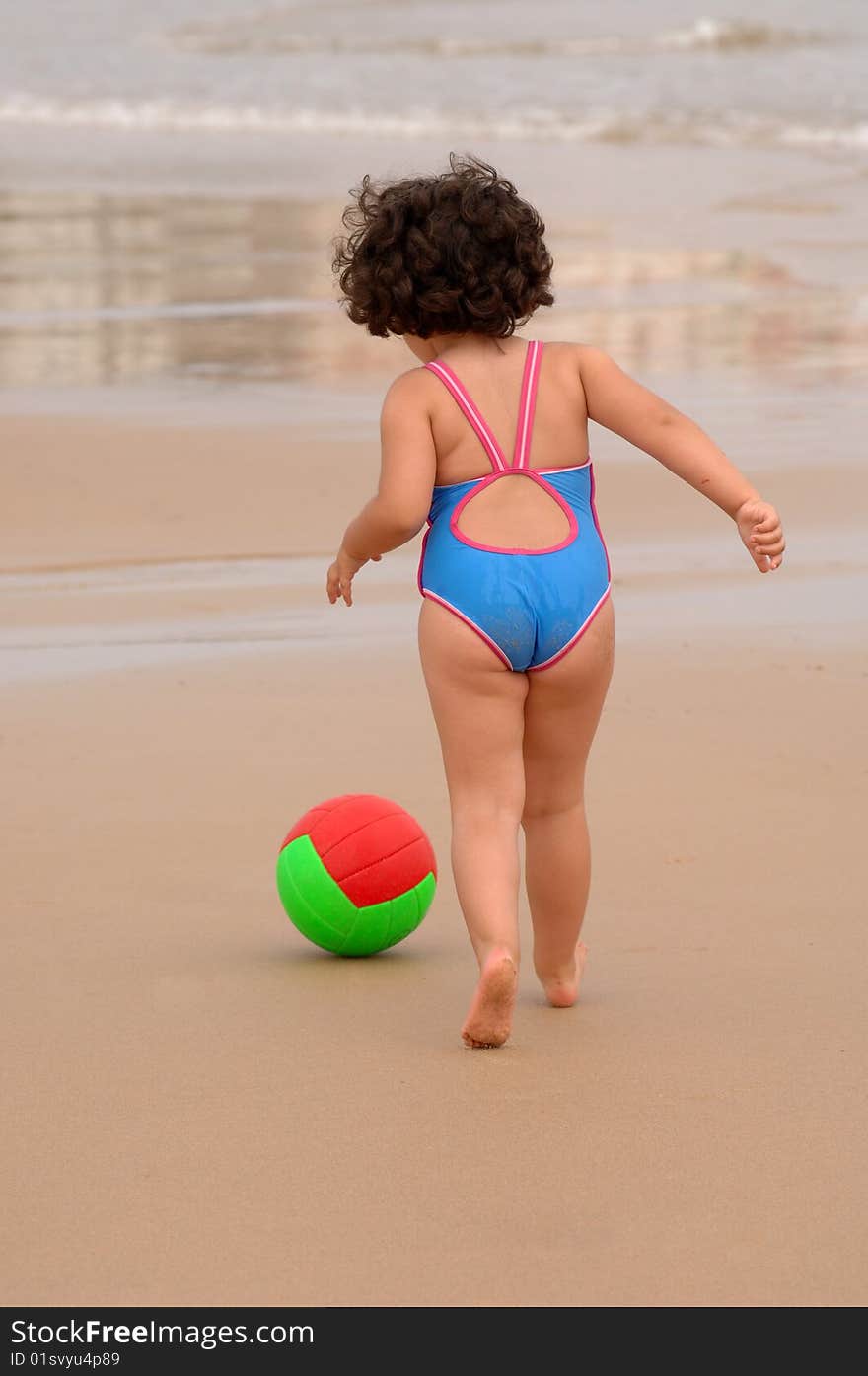 Cute little girl on the beach playing with a ball