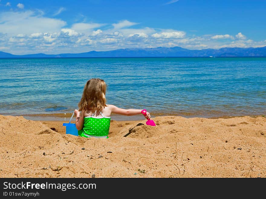 Girl playing in the sand at the lake