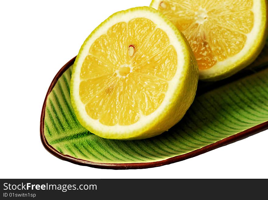 Cut lemons on green dish isolated on white background