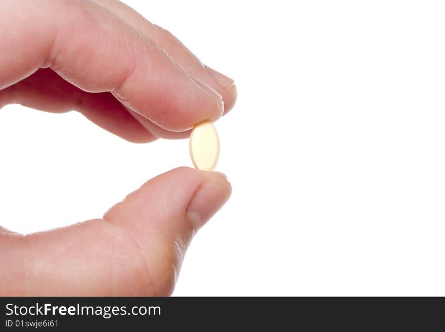 Two fingers holding a small cream prescription pill. Two fingers holding a small cream prescription pill