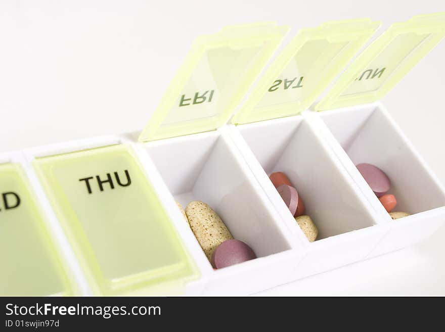 Weekly pill organizer with an assortment of pills and vitamins inside