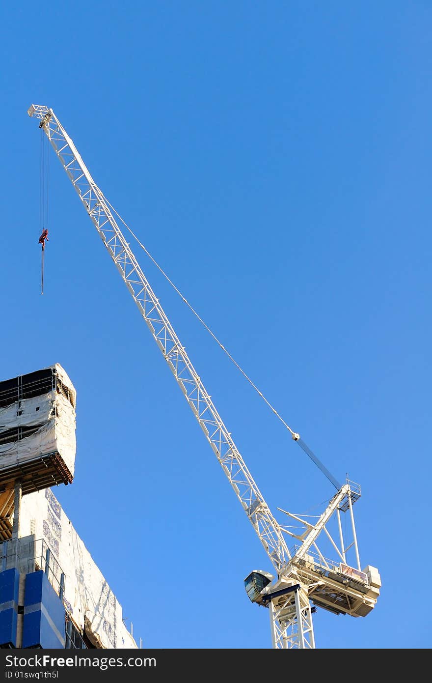 White construction crane with blue sky on background