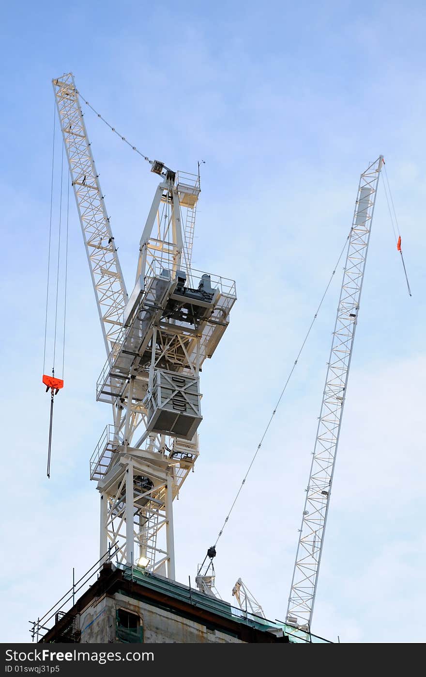 Two white construction cranes with blue sky on background. Two white construction cranes with blue sky on background