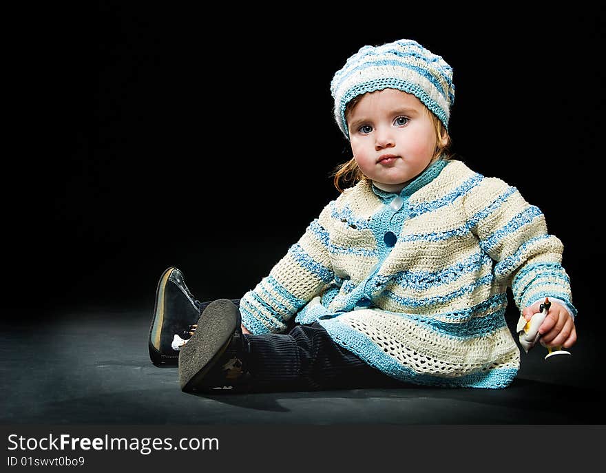 Sitting little baby in a bound suit on black background