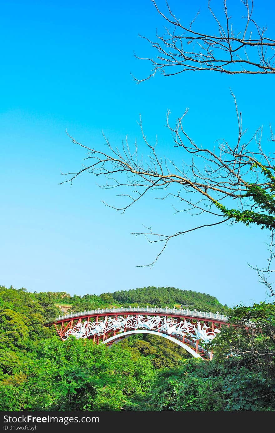 Unique bridge surrounded with nature with barren tree branches in the foreground