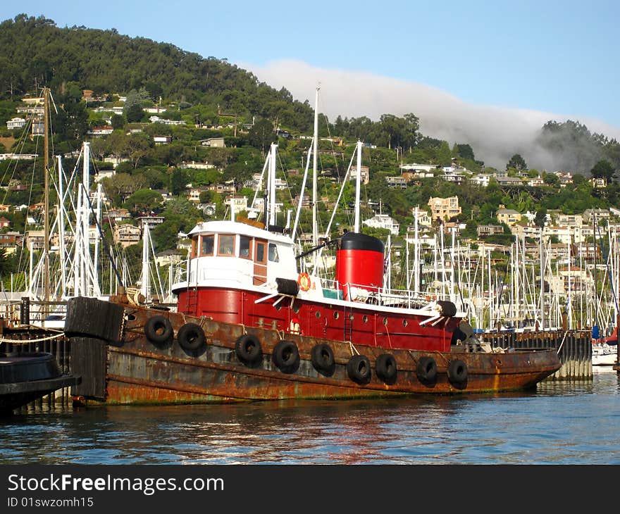 Rusty old red tugboat docked in Sausalito harbor.