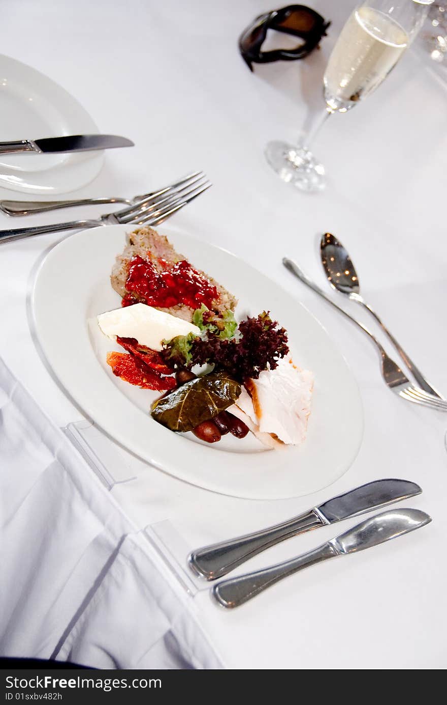 Place setting with meal including utensils and wine in glass