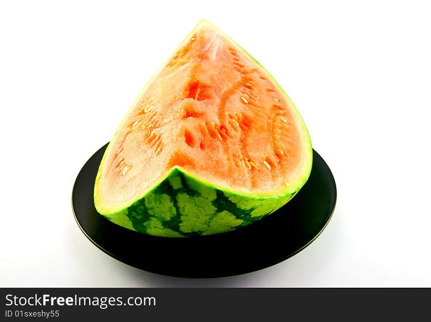 Slice of watermelon with green skin and red melon with seeds on a black plate with a white background. Slice of watermelon with green skin and red melon with seeds on a black plate with a white background