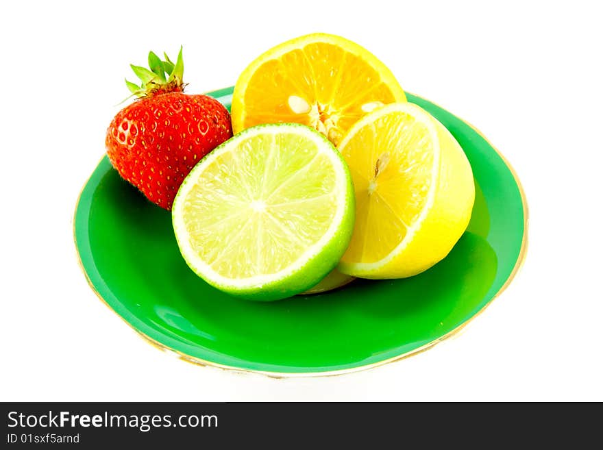 Lemon, lime and orange halves on a fancy green plate with a red juicy strawberry on a white background. Lemon, lime and orange halves on a fancy green plate with a red juicy strawberry on a white background