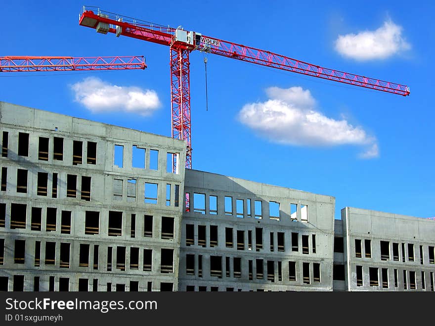 On a photo: Building and crane on a background of the blue sky.