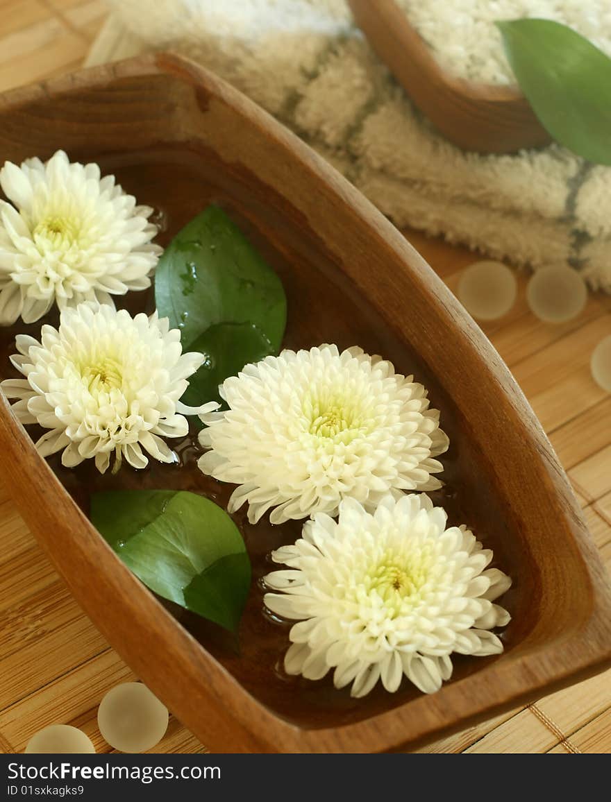 White flowers floating in wooden bowl. spa background