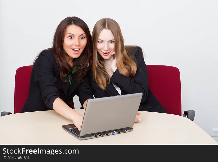 Two business women with surprised look at the laptop screen