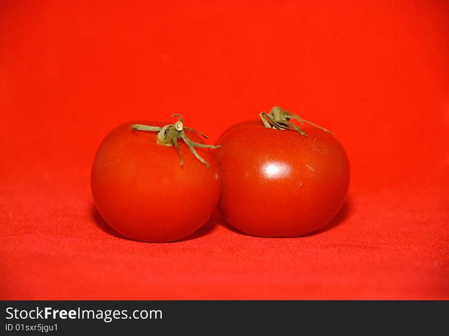 Red tomatos with stalks on red background. Red tomatos with stalks on red background