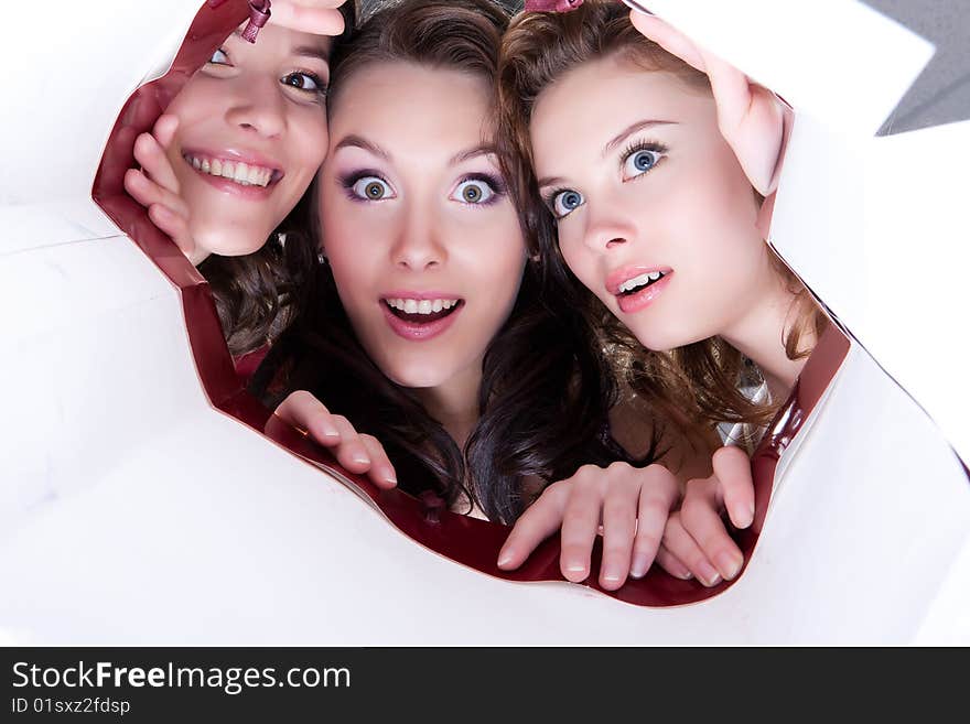 Young women look into the shopping bag surprisingly. Young women look into the shopping bag surprisingly