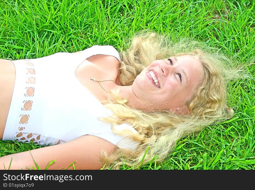 Pretty blonde girl on green grass.