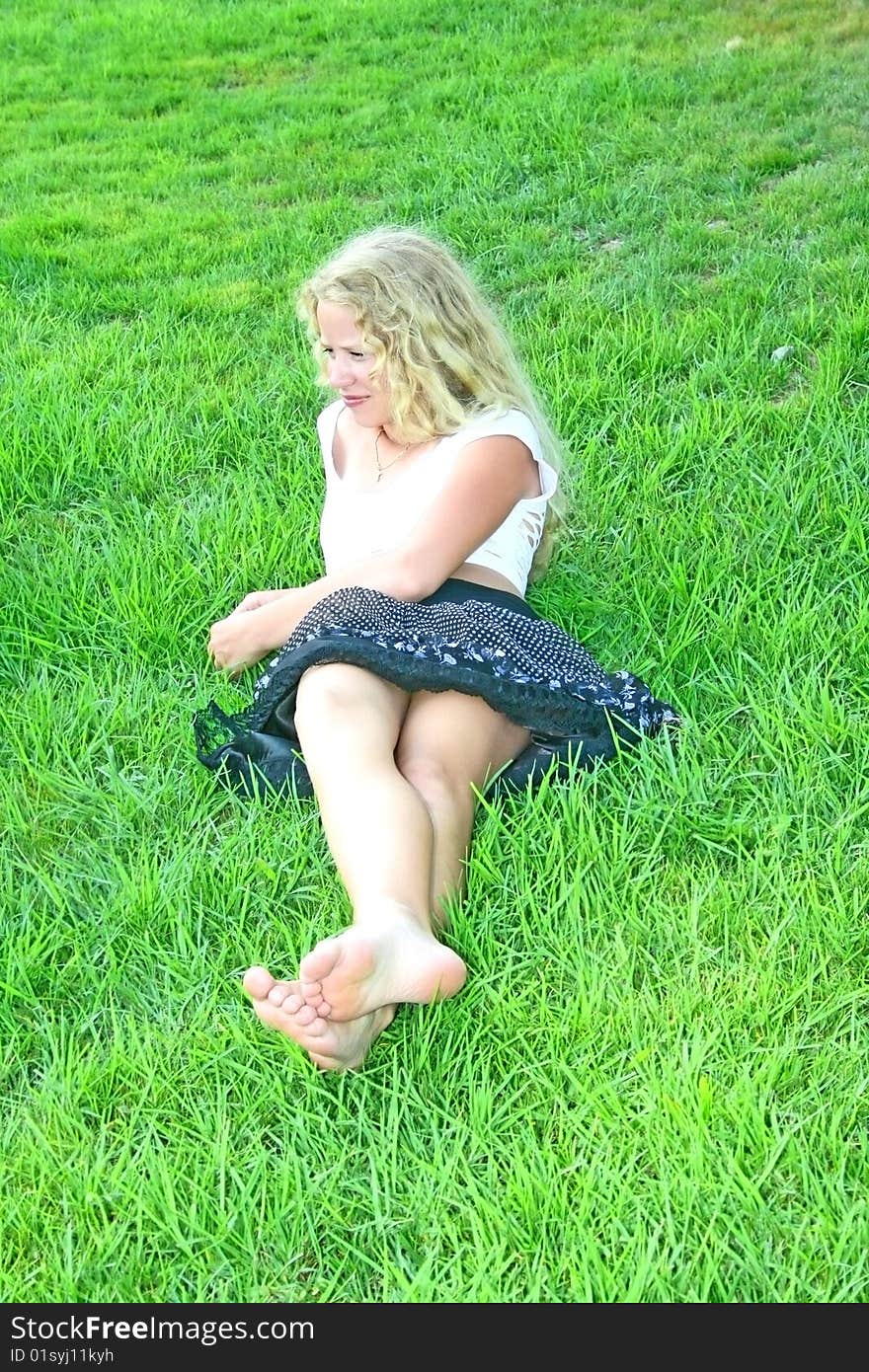 Pretty blonde girl on green grass.