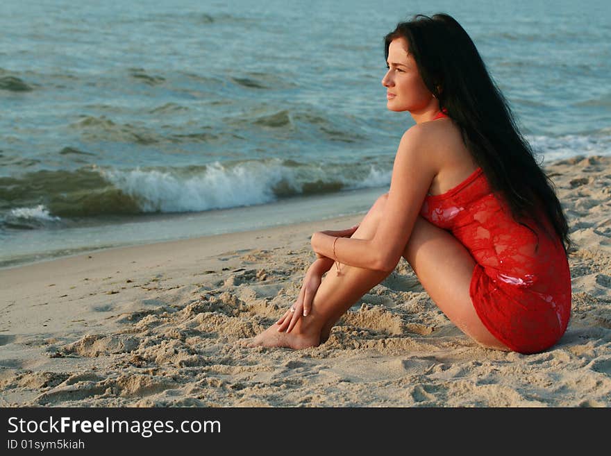 Beautiful girl is sitting on the beach