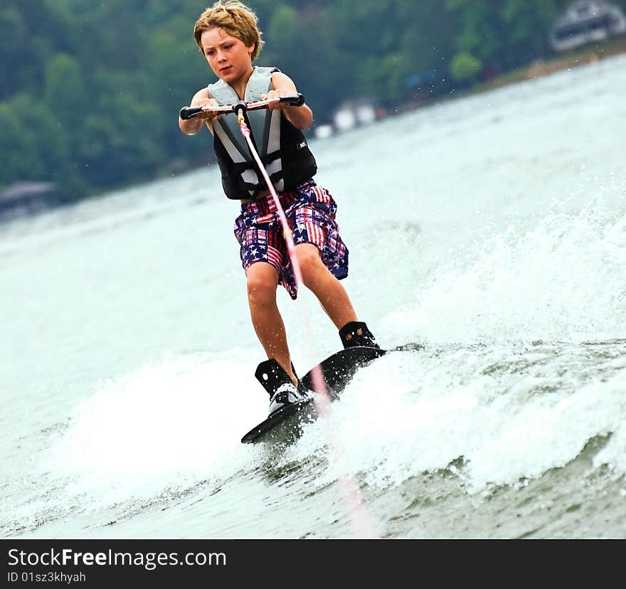 A young boy (9years old) concentrating while crossing the wake on his trick skis. A young boy (9years old) concentrating while crossing the wake on his trick skis.