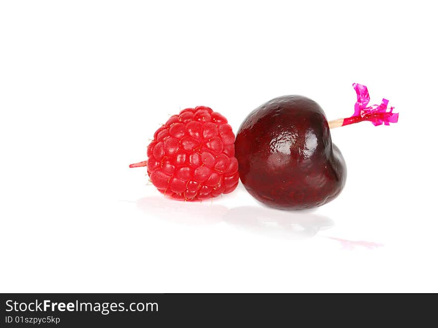 Black fresh ripe cherry with ruspberry on the wood pick isolated on the hate background. Black fresh ripe cherry with ruspberry on the wood pick isolated on the hate background.