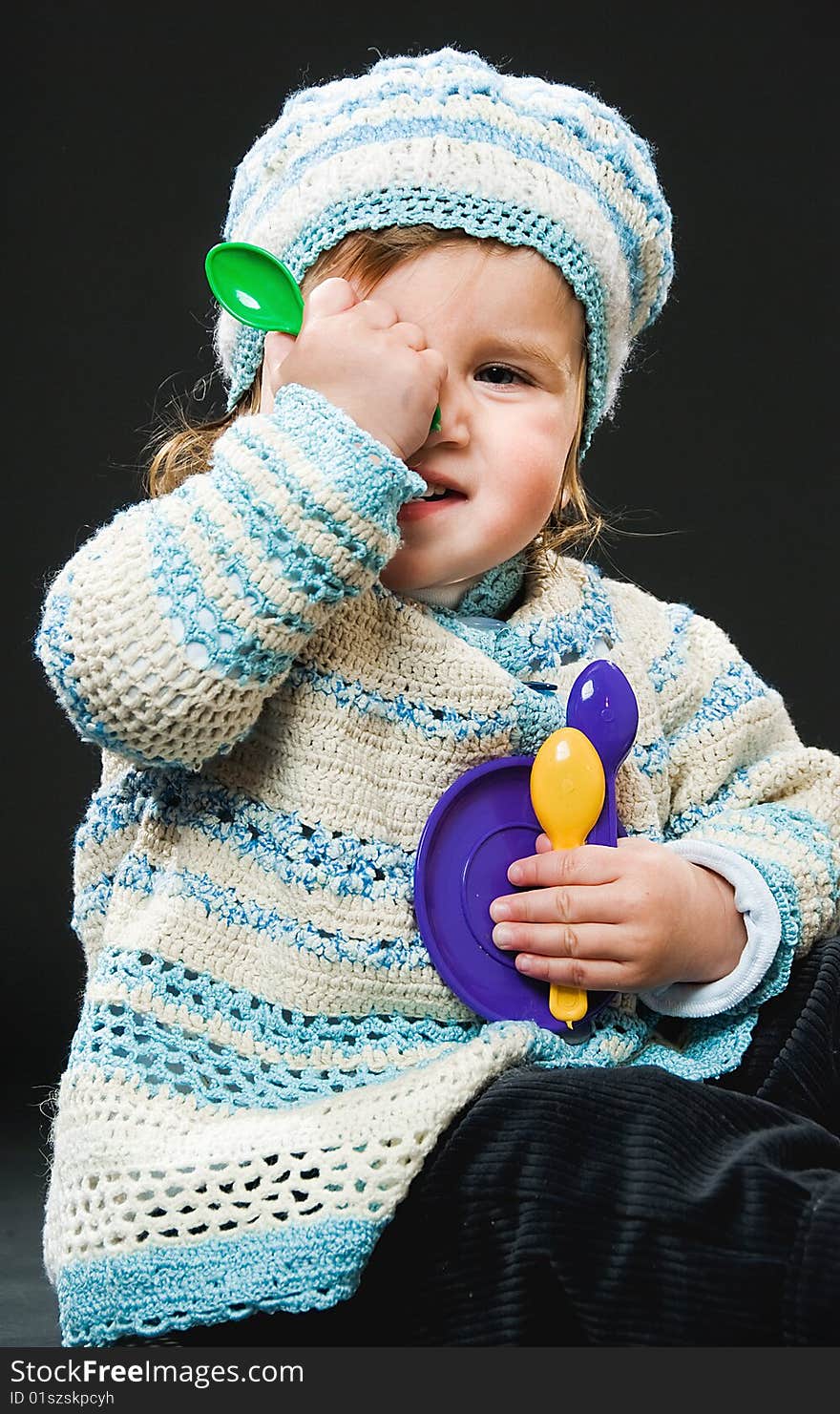 Little girl in bound suit with toys on black background