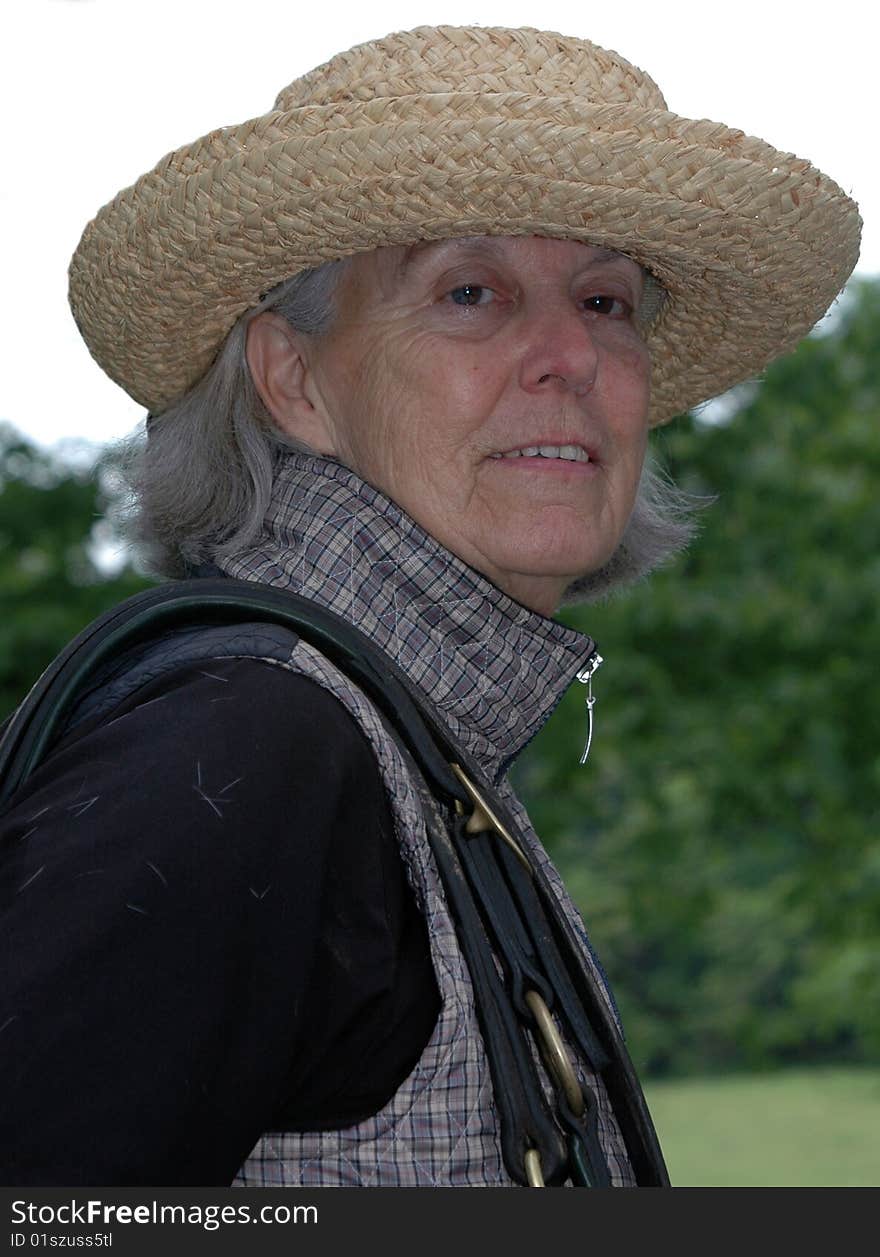 Color photograph of a senior woman on her way to saddle up her horse. Color photograph of a senior woman on her way to saddle up her horse.