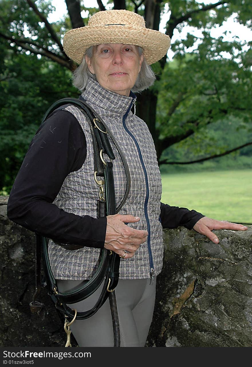 Color photograph of a senior equestrian getting ready to saddle up her horse for a ride. Color photograph of a senior equestrian getting ready to saddle up her horse for a ride.