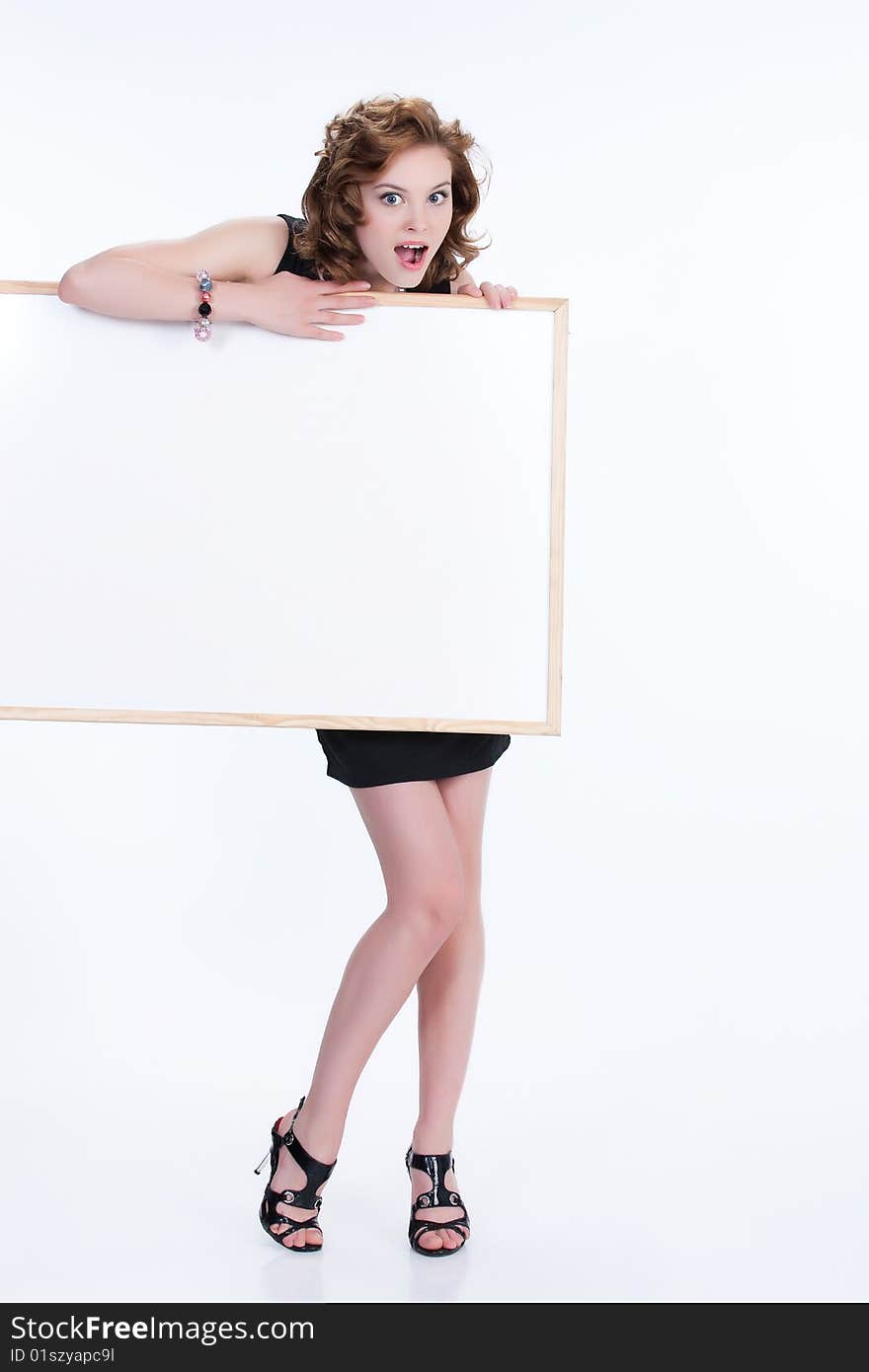 Young emotional woman on isolated background holding a blank board