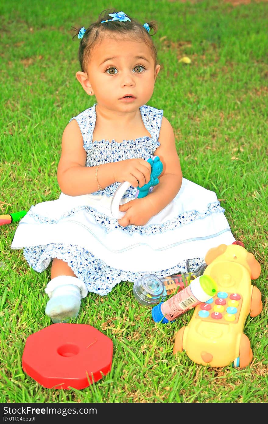 Little brunette girl with toys on green grass. Little brunette girl with toys on green grass.