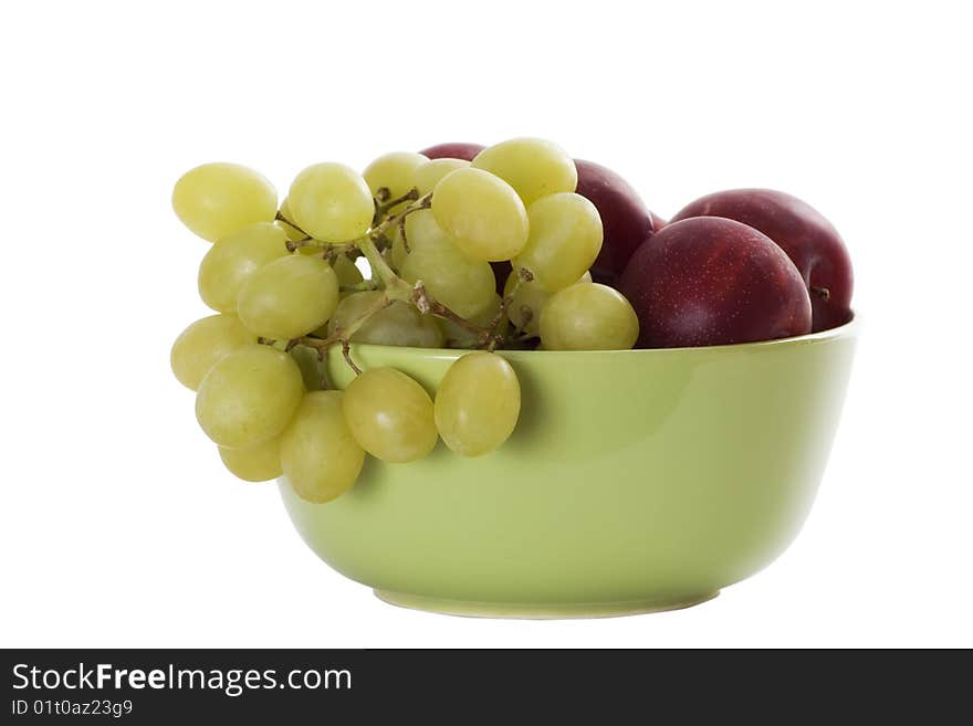 Isolated green bowl with red plums and green grapes. Isolated green bowl with red plums and green grapes