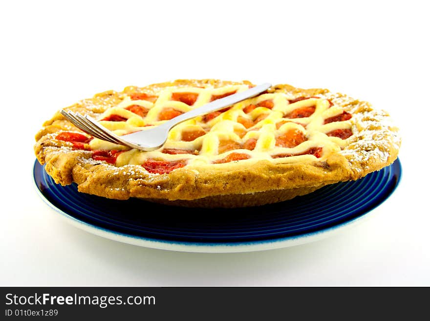 Whole apple and strawberry pie on a blue plate with a small fork on a white background. Whole apple and strawberry pie on a blue plate with a small fork on a white background