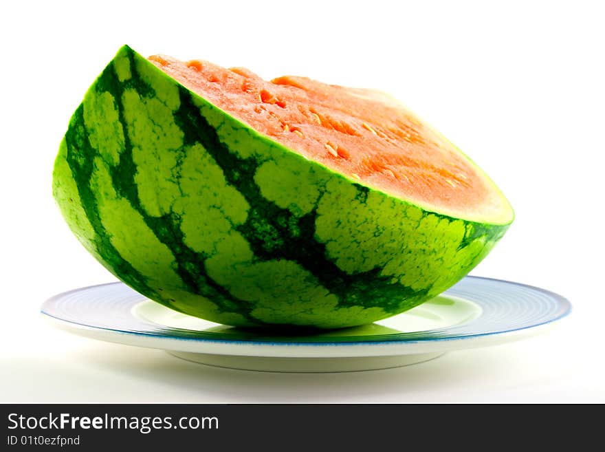 Slice of watermelon with green skin and red melon with seeds on a blue plate with a white background