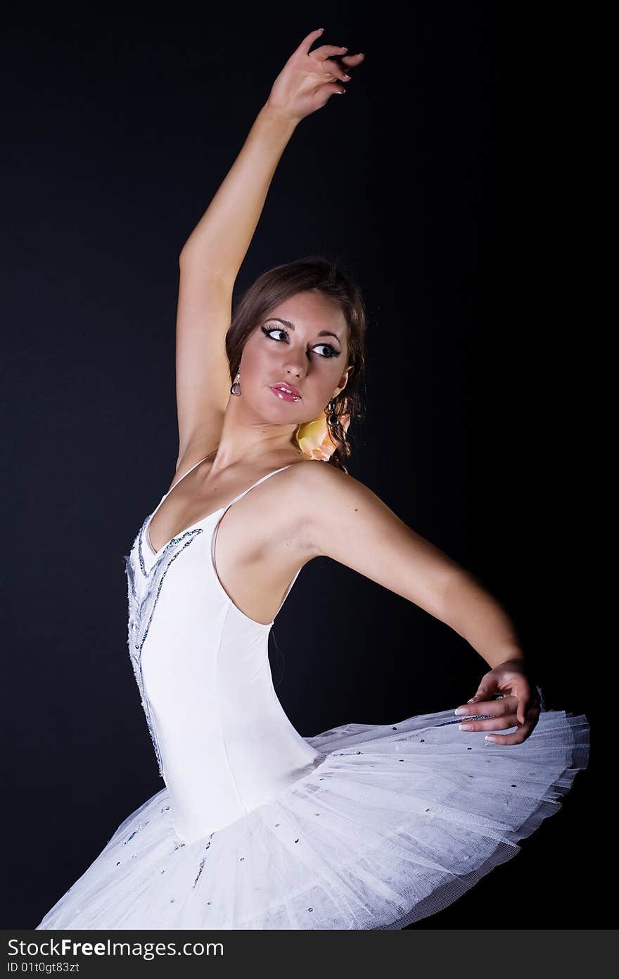 Ballerina in white tutu on black background