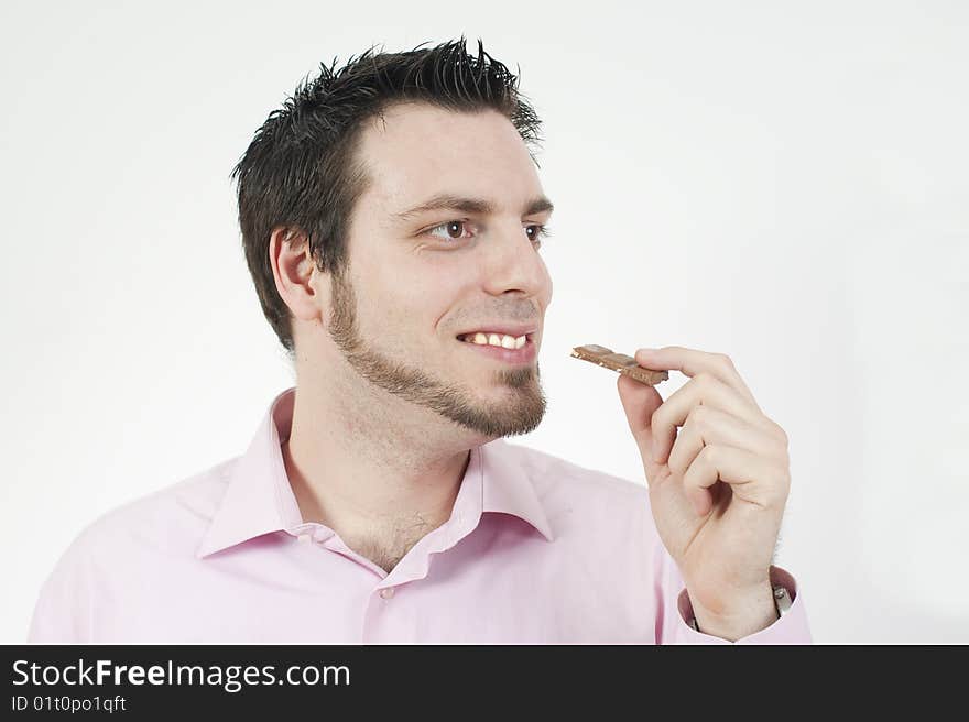 Handsome man eating a chocolate