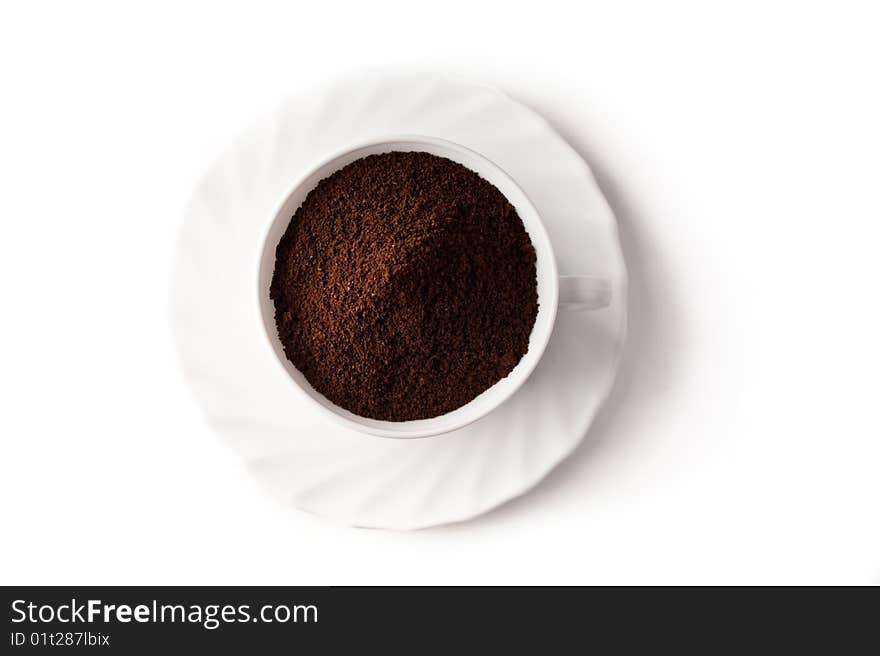 Pile of ground coffee in a cup is isolated against a white background