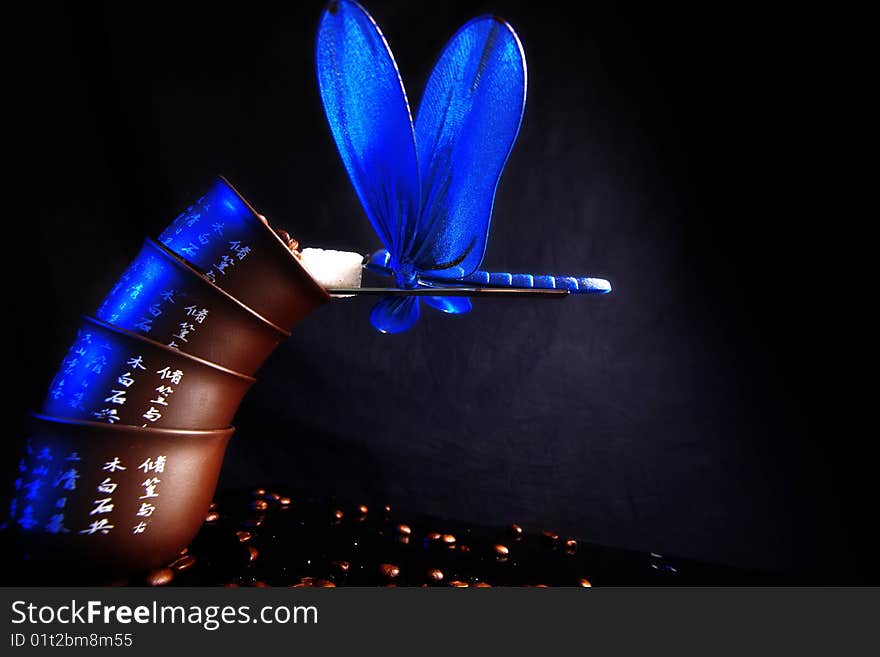 Balance - blue dragonfly at beans of coffee with sugar. Balance - blue dragonfly at beans of coffee with sugar