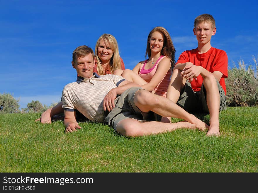 Family of four sit on grass