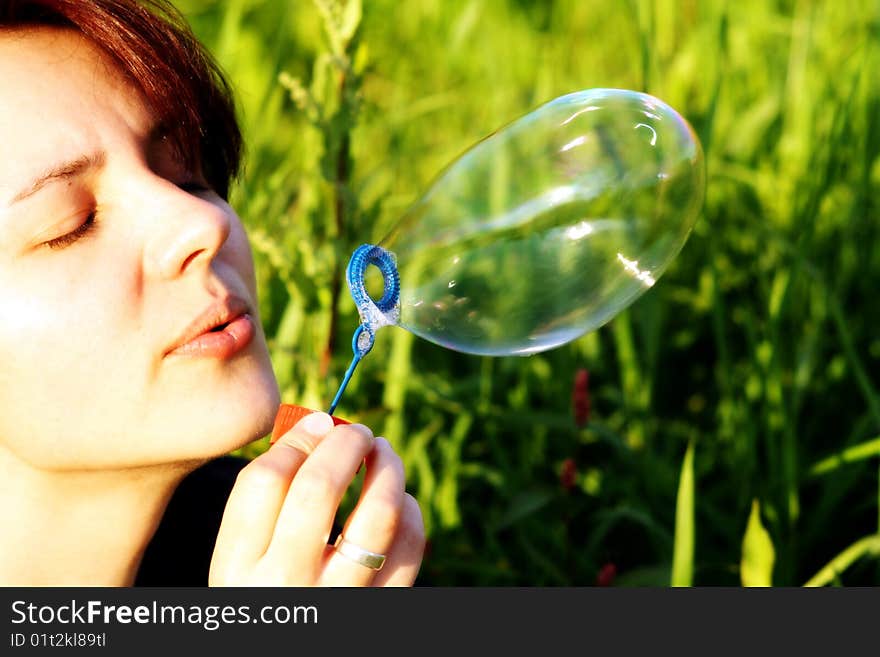 A woman is blowing a  bubble